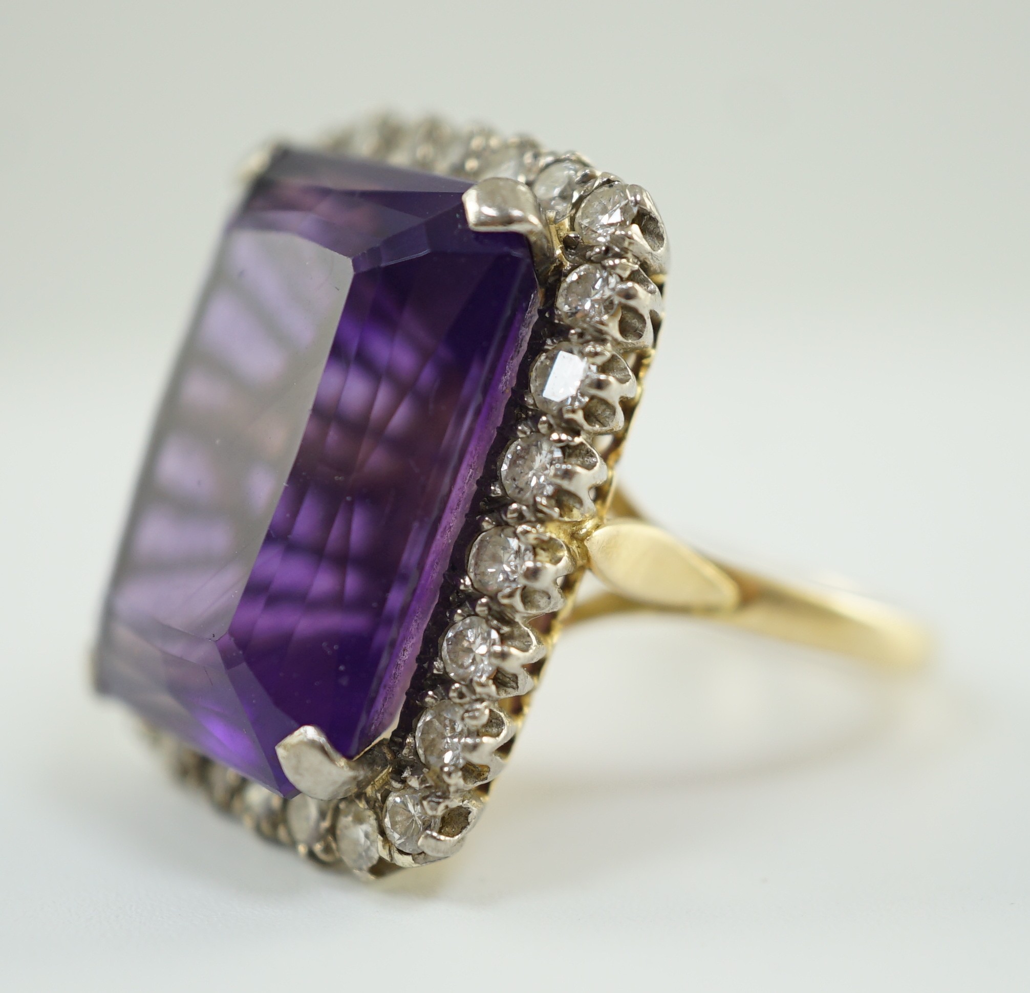 A large modern 18ct gold and emerald cut amethyst set dress ring, with diamond set border